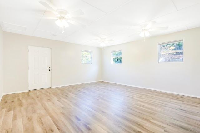 spare room featuring light wood finished floors, attic access, and baseboards