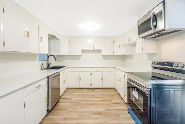 kitchen featuring stainless steel appliances, white cabinets, a sink, and light wood finished floors