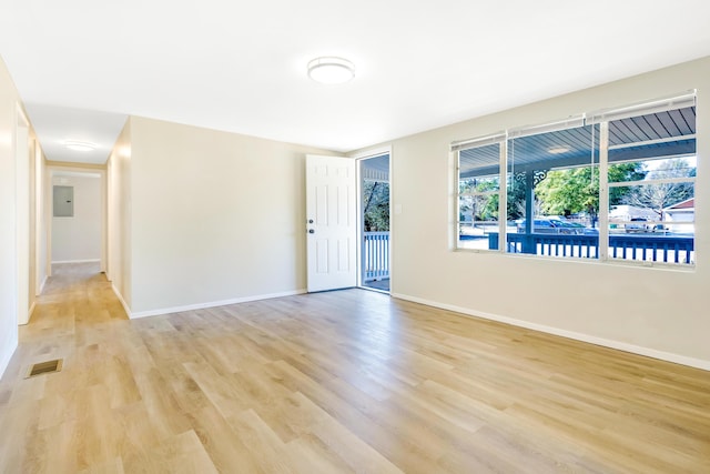 spare room featuring baseboards, electric panel, visible vents, and light wood-style floors