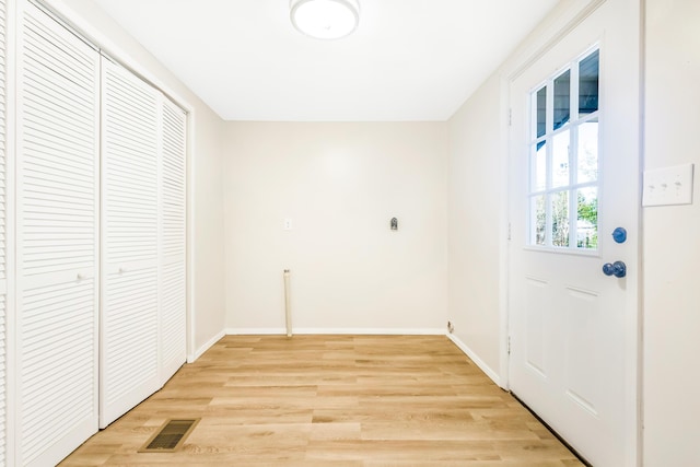 interior space with laundry area, light wood finished floors, visible vents, and baseboards