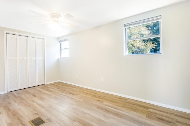 unfurnished bedroom with a closet, visible vents, light wood-style floors, ceiling fan, and baseboards