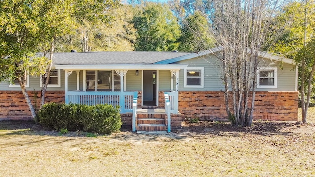 view of front of house featuring a porch, crawl space, brick siding, and a shingled roof