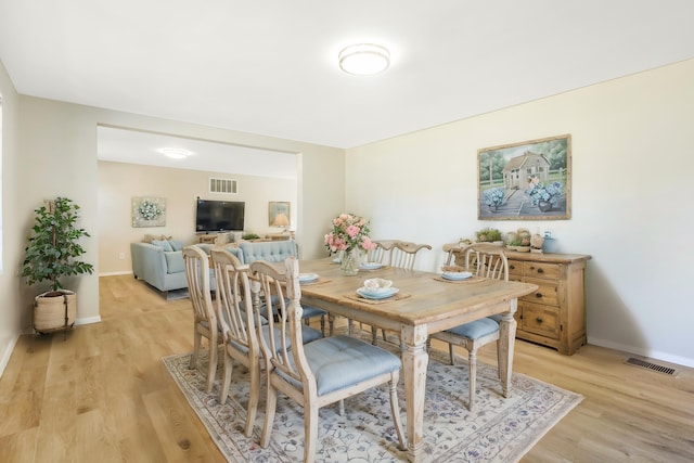 dining space with light wood-style floors, baseboards, and visible vents