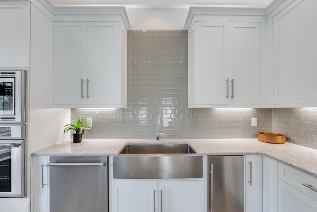 41 Tresca Lake Ct, Santa Rosa Beach, FL 32459 - kitchen with stainless steel appliances, white cabinets, tasteful backsplash, and light stone countertops