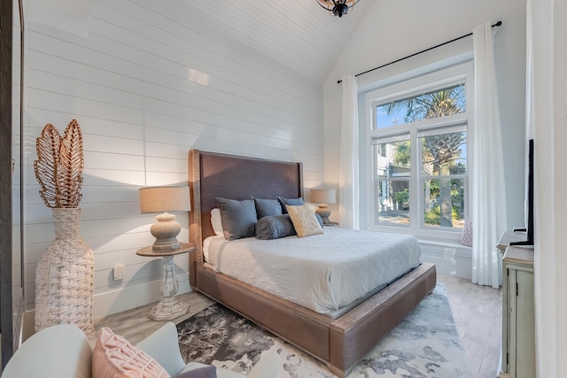 bedroom featuring vaulted ceiling and wood walls