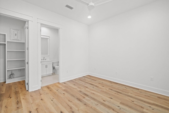 unfurnished bedroom featuring ceiling fan, light hardwood / wood-style floors, sink, and ensuite bath