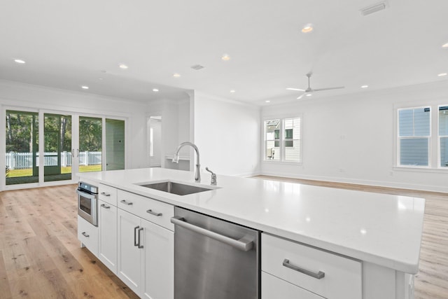 kitchen featuring open floor plan, stainless steel appliances, a sink, and light wood-style floors