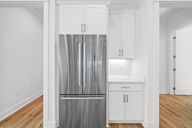 kitchen featuring tasteful backsplash, stainless steel refrigerator, white cabinets, and light hardwood / wood-style floors