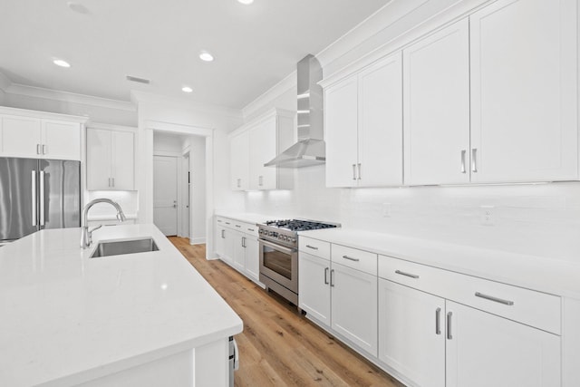 kitchen with white cabinetry, wall chimney range hood, sink, and appliances with stainless steel finishes