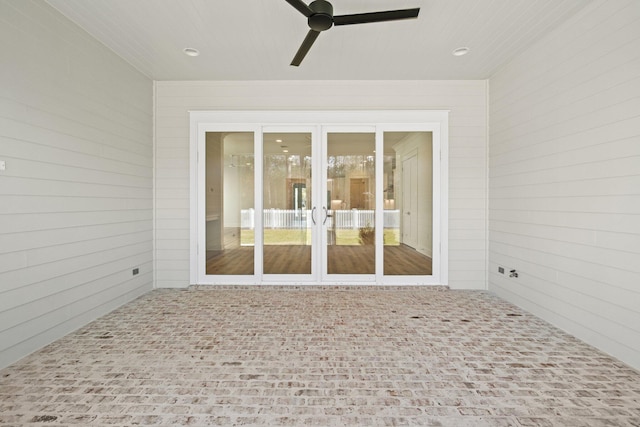 interior space with wood walls, brick floor, and a ceiling fan