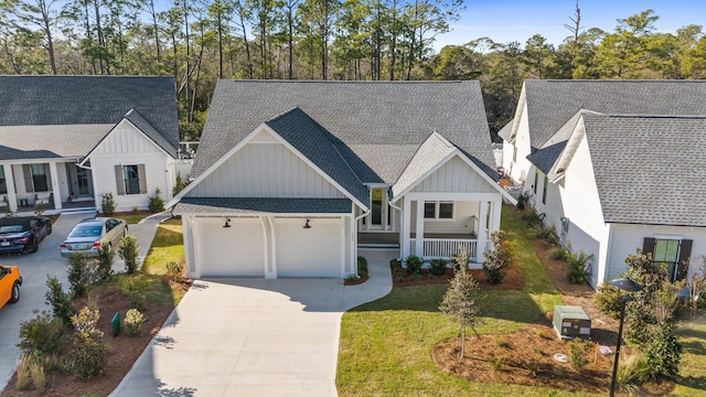 view of front facade with a garage, driveway, a porch, a front lawn, and board and batten siding