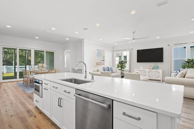 kitchen with stainless steel appliances, open floor plan, a sink, and light wood-style flooring