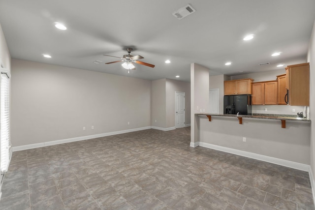 kitchen featuring ceiling fan, a breakfast bar, kitchen peninsula, and black fridge with ice dispenser