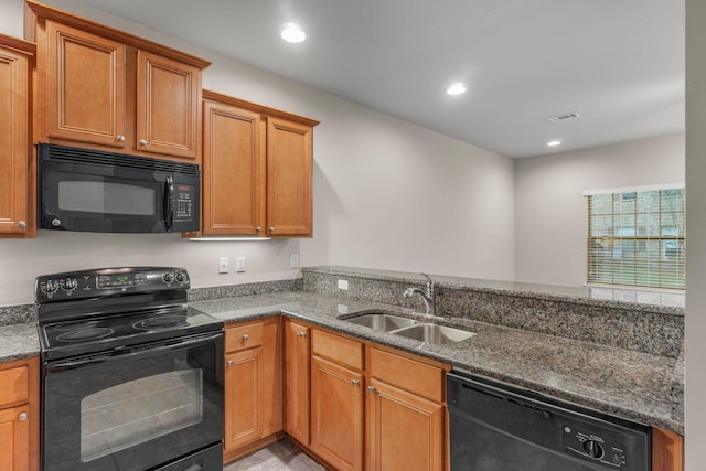 kitchen featuring black appliances, dark stone counters, and sink