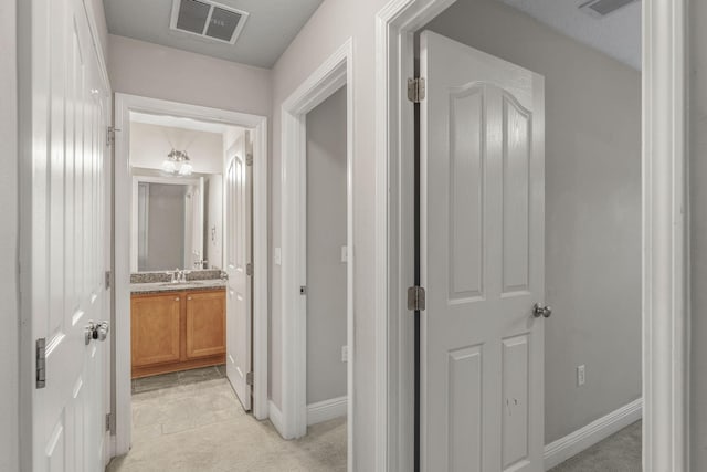 corridor with light colored carpet and sink