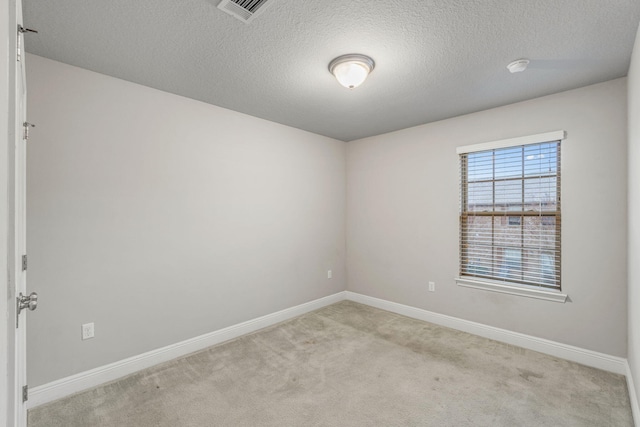 carpeted empty room featuring a textured ceiling