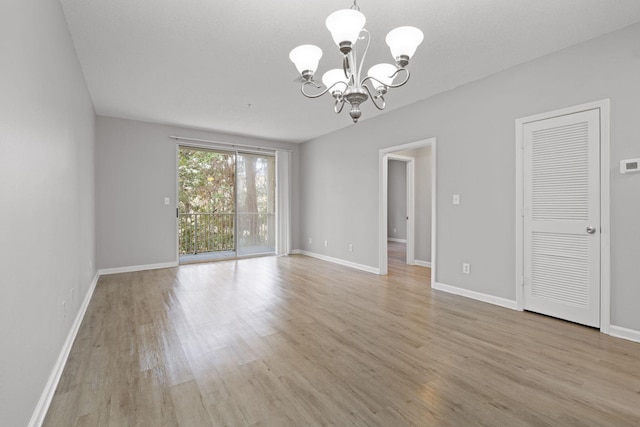 empty room featuring light wood-type flooring and an inviting chandelier