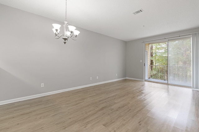 empty room with a notable chandelier and wood-type flooring