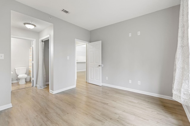 unfurnished bedroom with ensuite bath and light hardwood / wood-style floors