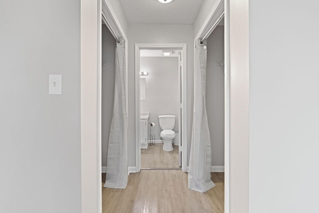 hall with light hardwood / wood-style floors and a textured ceiling