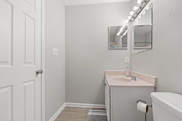 bathroom with hardwood / wood-style flooring, vanity, a textured ceiling, and toilet