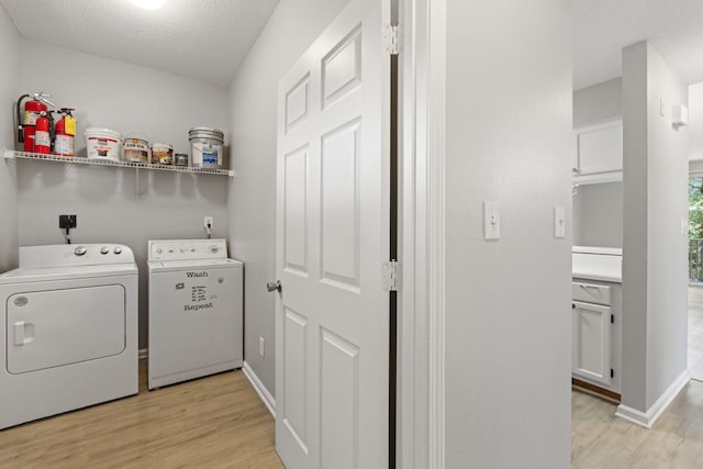 washroom with washer and clothes dryer, a textured ceiling, and light hardwood / wood-style flooring