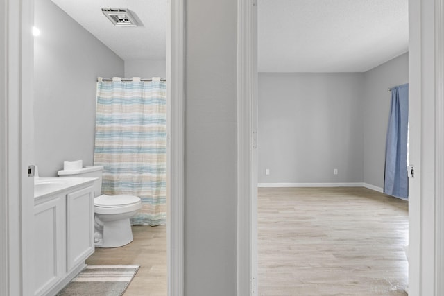 bathroom featuring walk in shower, vanity, a textured ceiling, hardwood / wood-style floors, and toilet