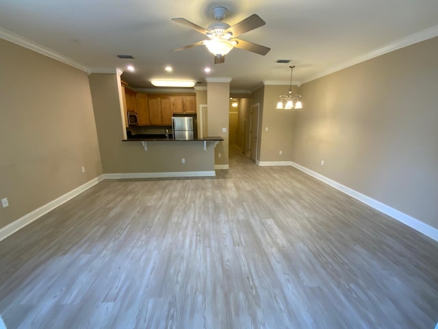 unfurnished living room with ceiling fan with notable chandelier, light hardwood / wood-style flooring, and crown molding