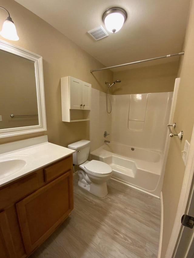 full bathroom featuring washtub / shower combination, vanity, hardwood / wood-style flooring, and toilet