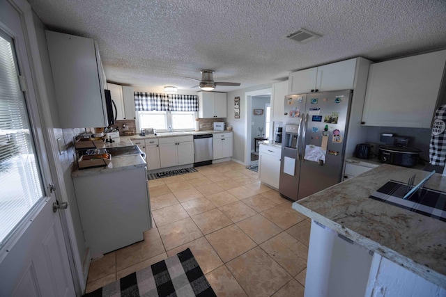 kitchen featuring ceiling fan, sink, stainless steel appliances, light tile patterned floors, and white cabinets