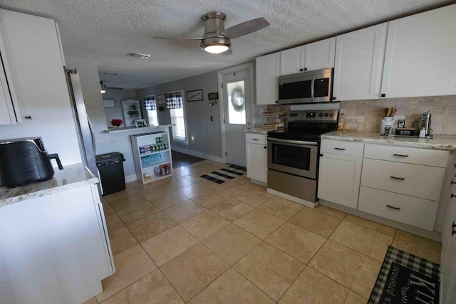 kitchen featuring a textured ceiling, ceiling fan, white cabinetry, and stainless steel appliances