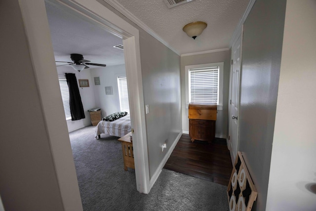 corridor with crown molding, dark carpet, and a textured ceiling