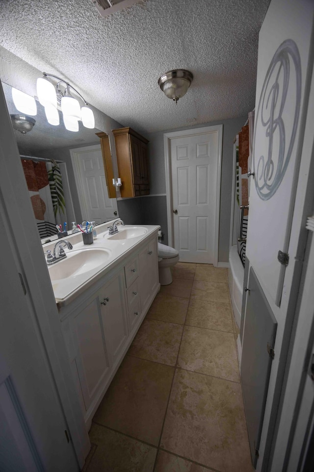 bathroom with tile patterned floors, vanity, toilet, and a textured ceiling