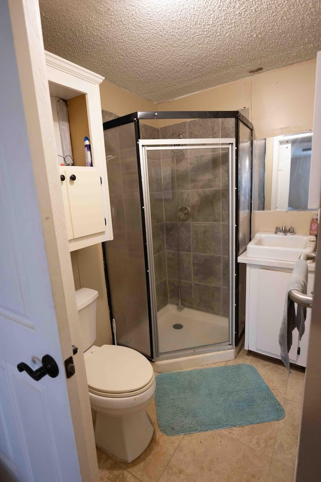 bathroom with tile patterned floors, a textured ceiling, toilet, vanity, and a shower with shower door