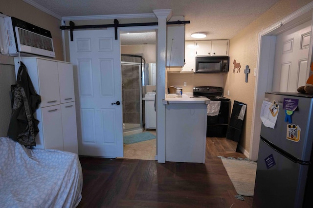 kitchen featuring a barn door, crown molding, a textured ceiling, white cabinets, and black appliances