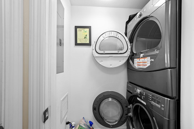 clothes washing area featuring a textured ceiling and stacked washing maching and dryer