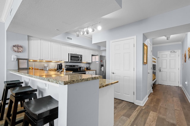 kitchen featuring kitchen peninsula, white cabinets, stainless steel appliances, and a textured ceiling