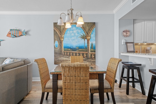 dining space with light hardwood / wood-style floors, ornamental molding, and a chandelier