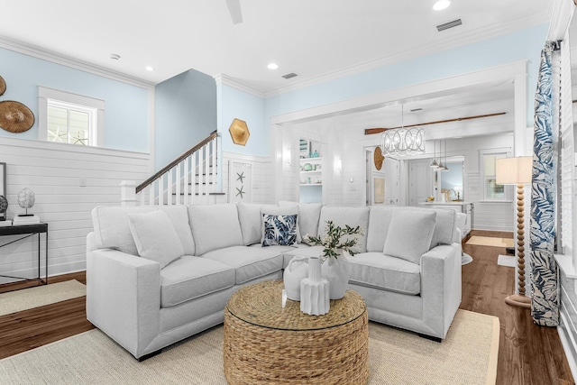 living room with an inviting chandelier, ornamental molding, and hardwood / wood-style floors