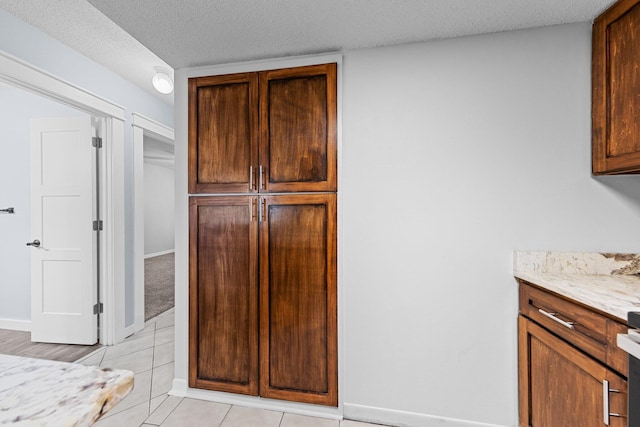 kitchen featuring a textured ceiling, range, light stone counters, and light tile patterned floors