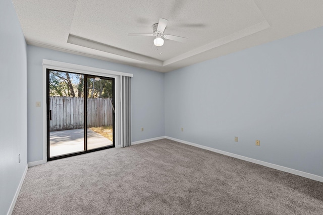 carpeted empty room with ceiling fan, a raised ceiling, and a textured ceiling