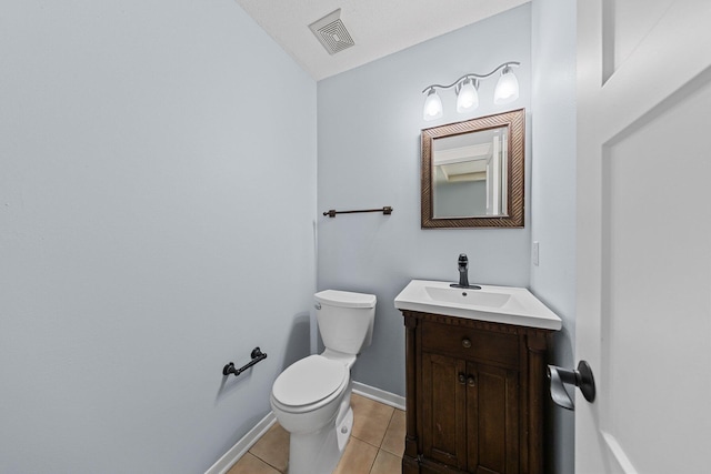 bathroom with toilet, vanity, and tile patterned floors