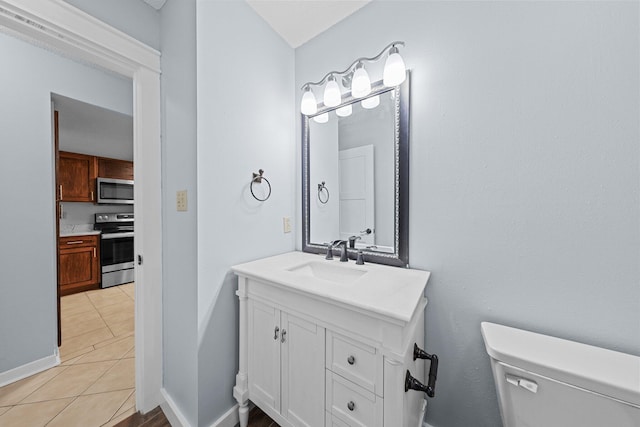 bathroom with toilet, vanity, and tile patterned floors