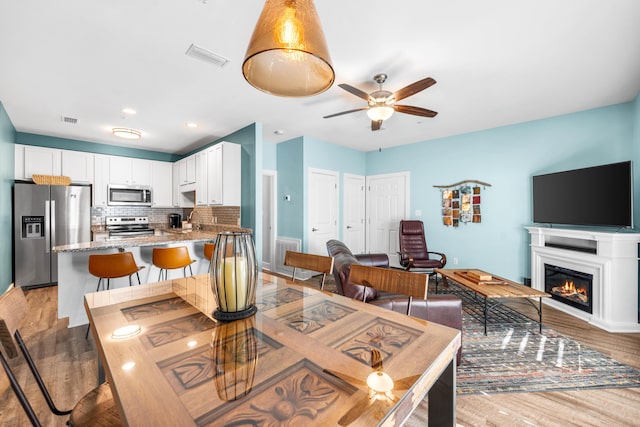 dining room with ceiling fan and light hardwood / wood-style flooring