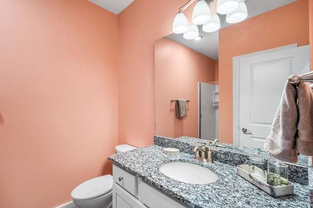 bathroom with vanity, a shower with shower door, and toilet