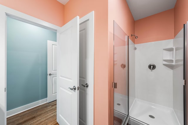 bathroom with hardwood / wood-style flooring and a shower with shower door