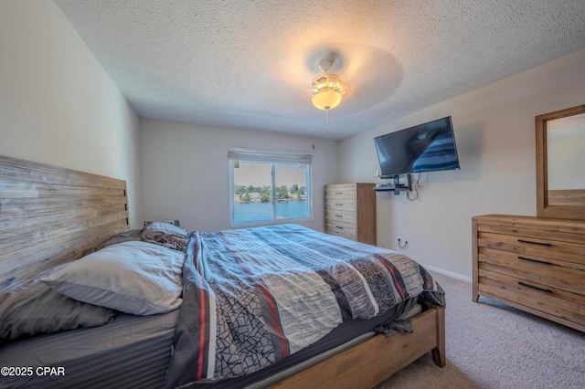 carpeted bedroom featuring ceiling fan and a textured ceiling