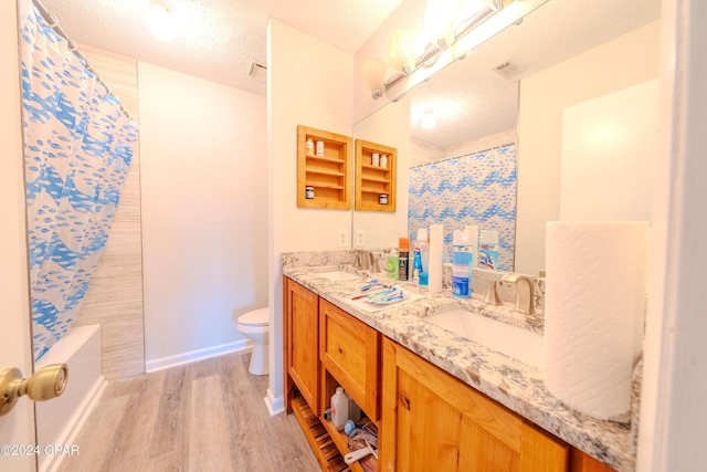 bathroom with hardwood / wood-style floors, vanity, a textured ceiling, and toilet