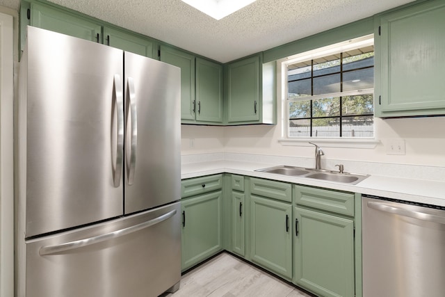 kitchen with sink, green cabinetry, a textured ceiling, light hardwood / wood-style floors, and stainless steel appliances