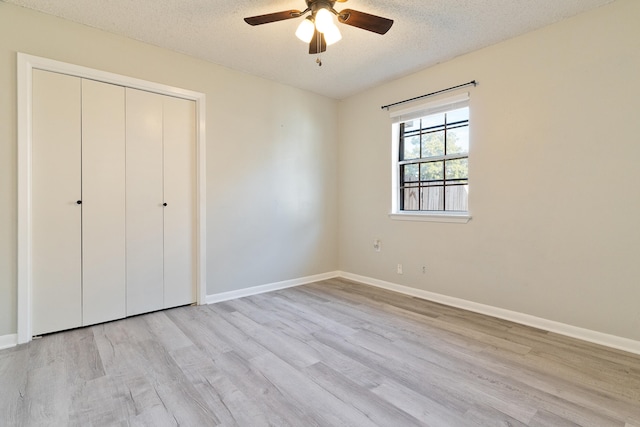 unfurnished bedroom with ceiling fan, light wood-type flooring, a textured ceiling, and a closet